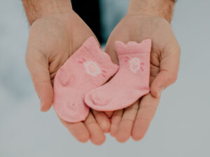 Dad holding small pink baby socks during maternity session in Houghton Michigan