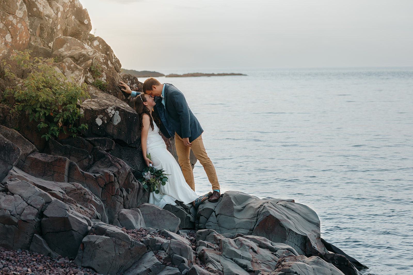Bride and groom share a moment on a rocky outcropping at Hunter's Point in Copper Harbor
