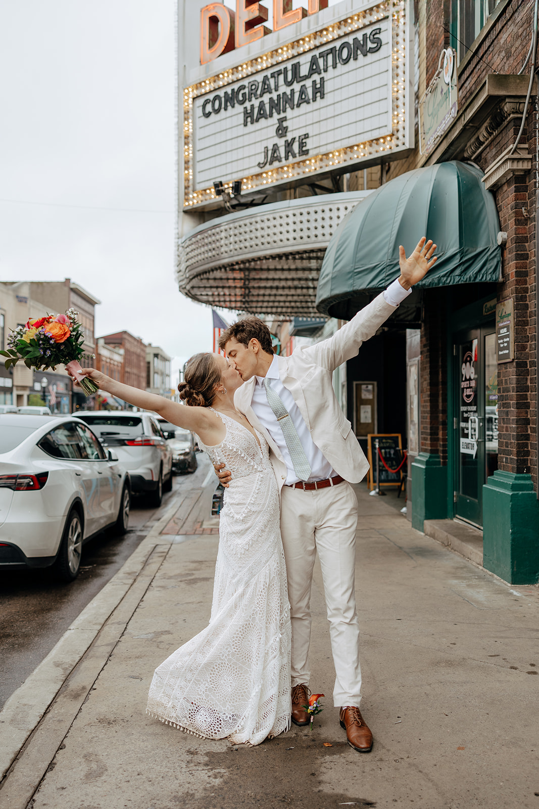 Bride and groom pose outside a the marquee of the Delft Bistro downtown Marquette on their wedding day