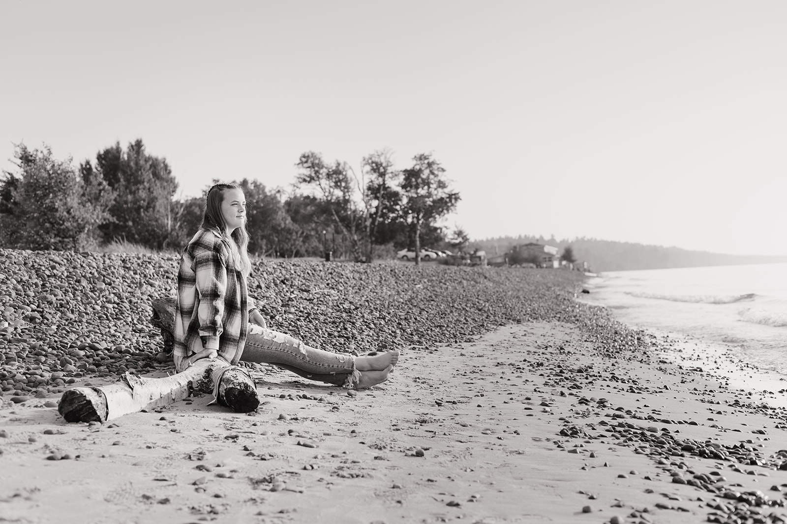 Senior enjoys senior photos in Eagle River Michigan on the beach with her dog in cozy flannel and jeans