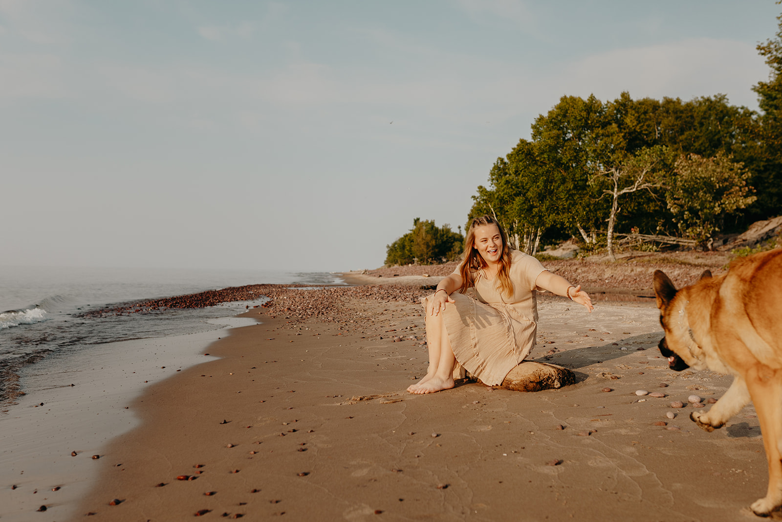 Senior enjoys senior photos in Eagle River Michigan on the beach with her dog in a day dress