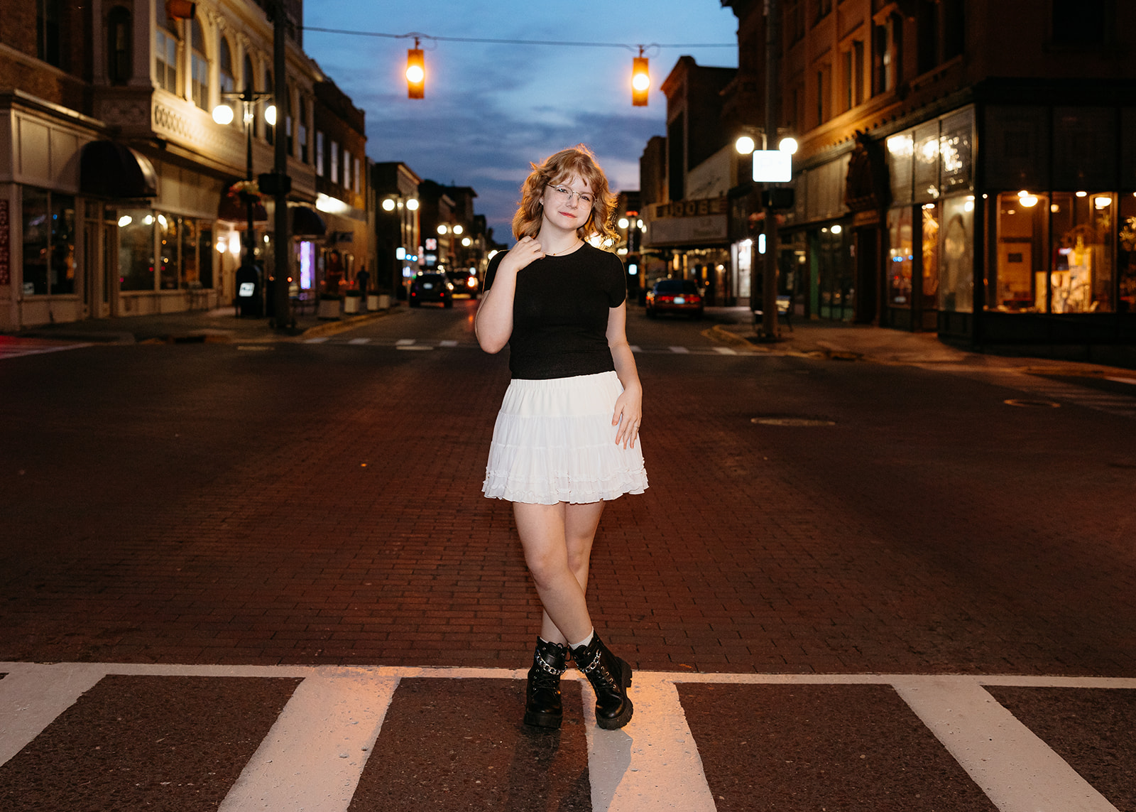 Highschool graduate poses in crosswalk downtown Houghton with ambient streetlights during her senior session in Houghton, Michigan